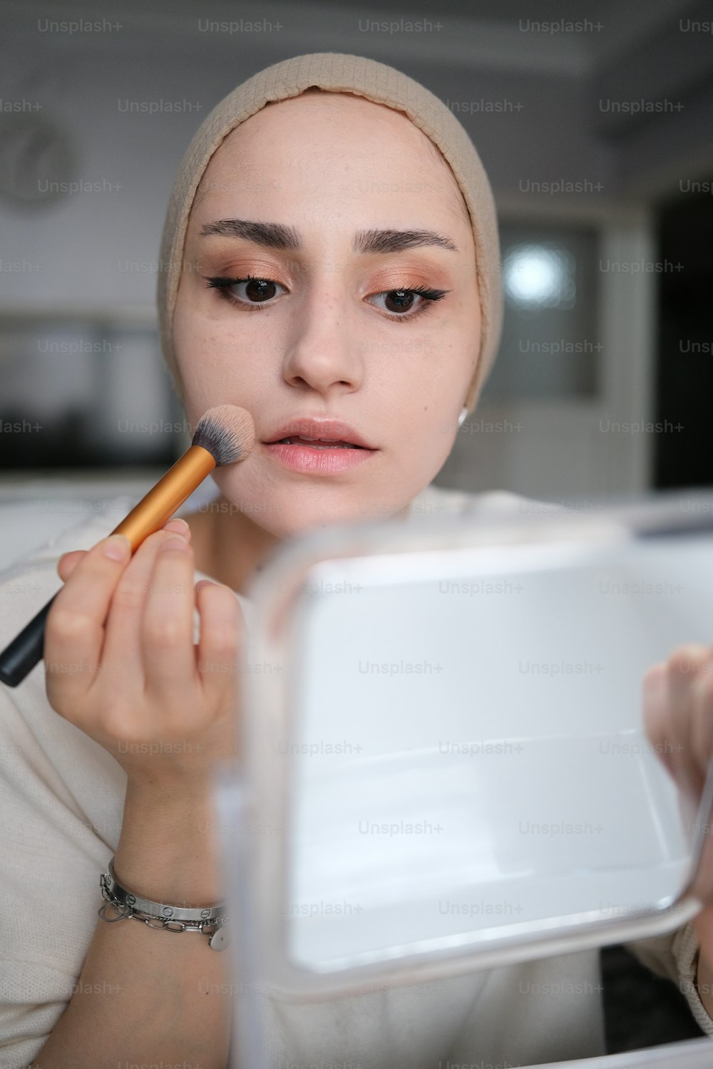 a woman is putting makeup on her face