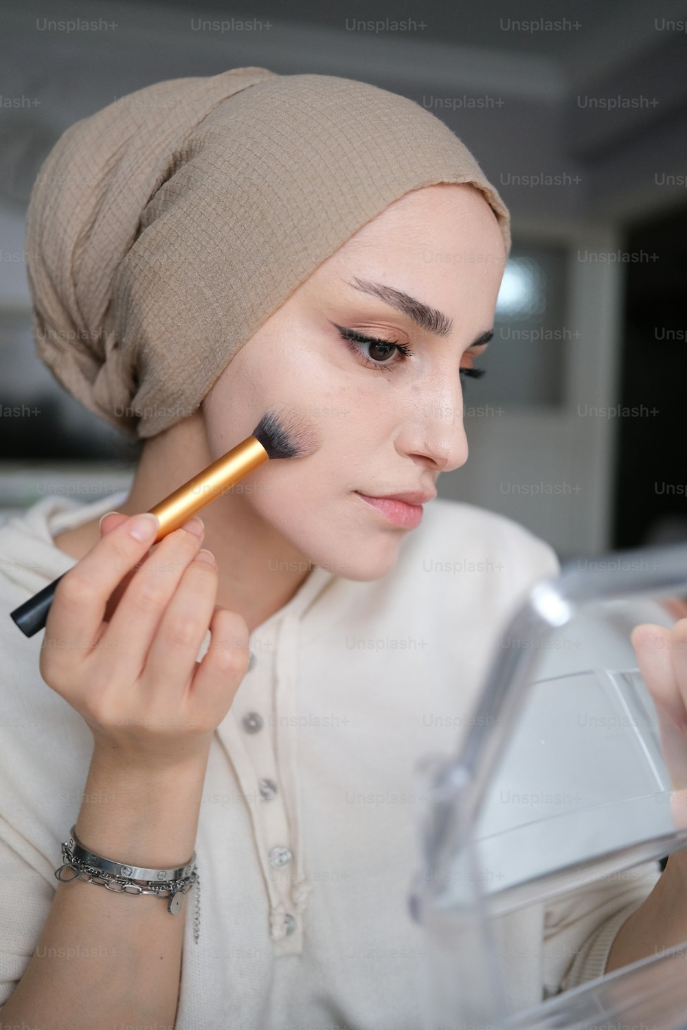 a woman with a turban on putting on makeup