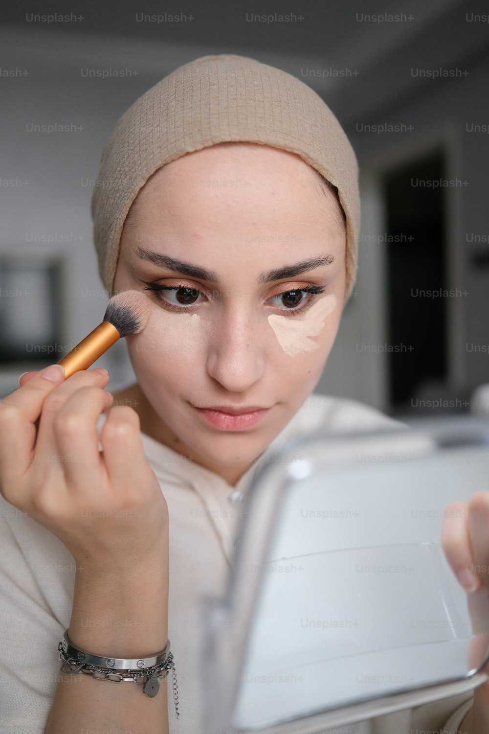 Una mujer está usando un pincel para aplicar maquillaje en su cara