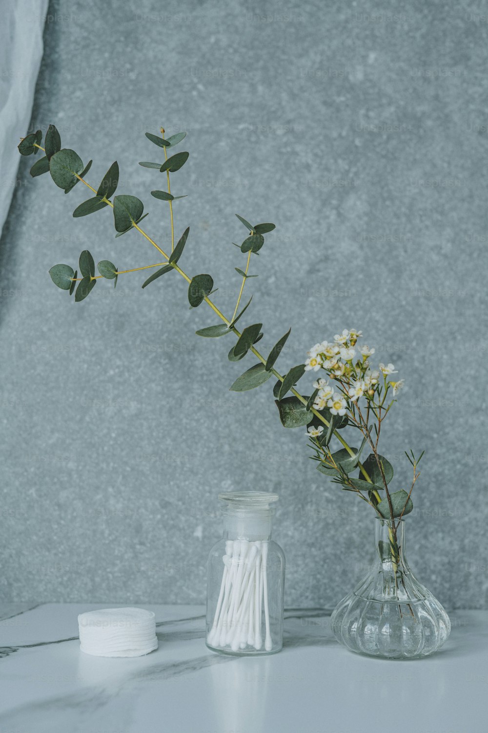 un vase rempli de fleurs à côté d’un récipient blanc