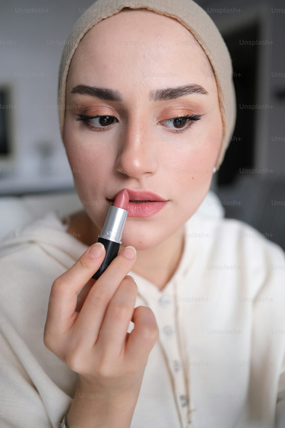 a woman is putting lipstick on her lips