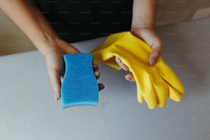una persona sosteniendo una esponja y un par de guantes