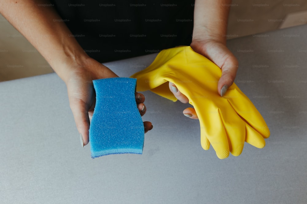 a person holding a sponge and a pair of gloves