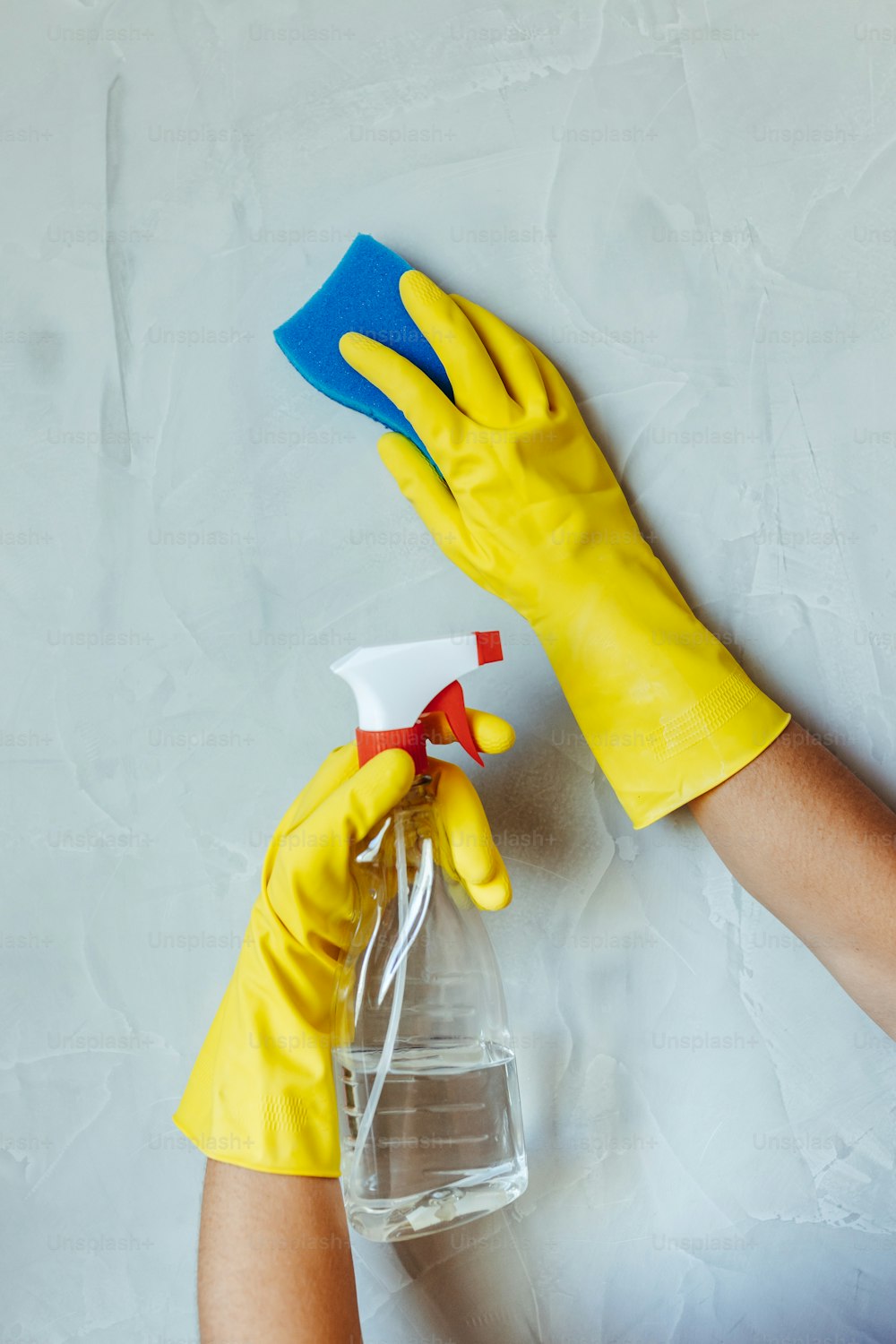 a person in yellow gloves and yellow rubber gloves holding a spray bottle