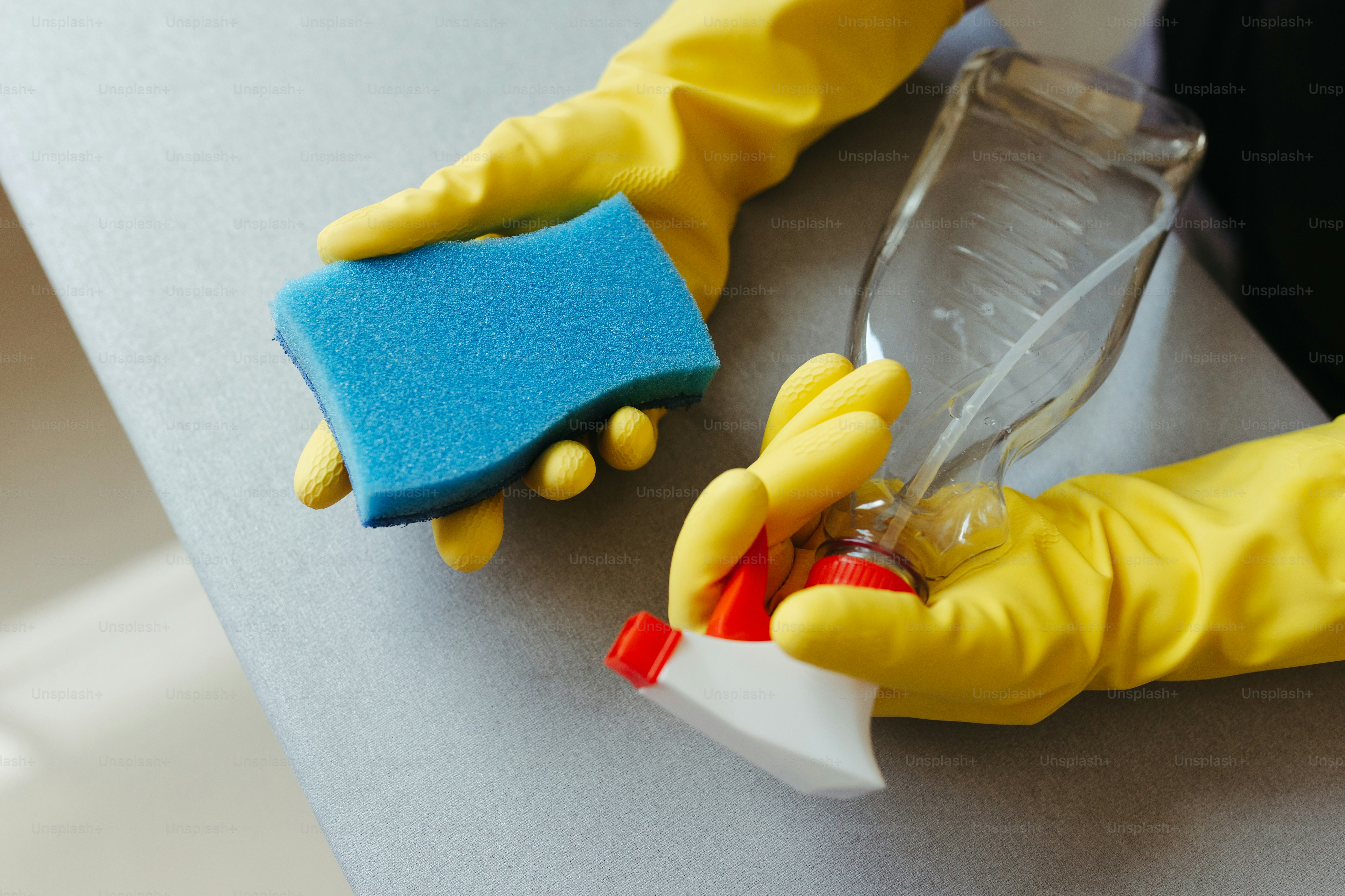 a person in yellow gloves is cleaning a table