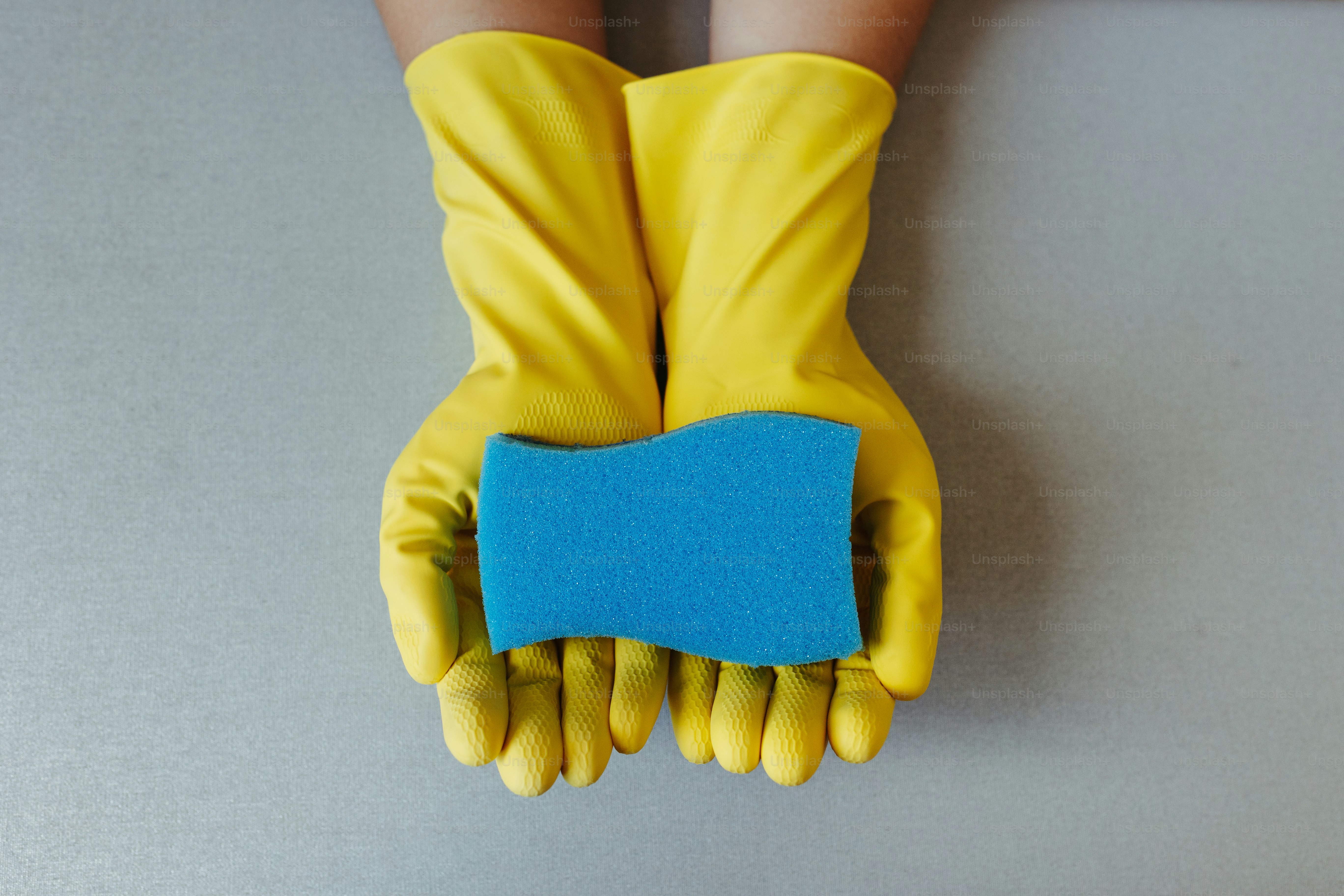 un par de guantes amarillos sosteniendo un pedazo de papel azul