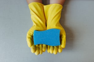 a pair of yellow gloves holding a blue piece of paper