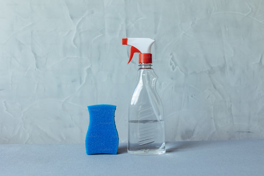 a bottle of cleaner next to a blue sponge
