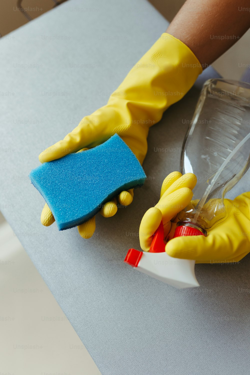 Una persona con guantes amarillos está limpiando una mesa