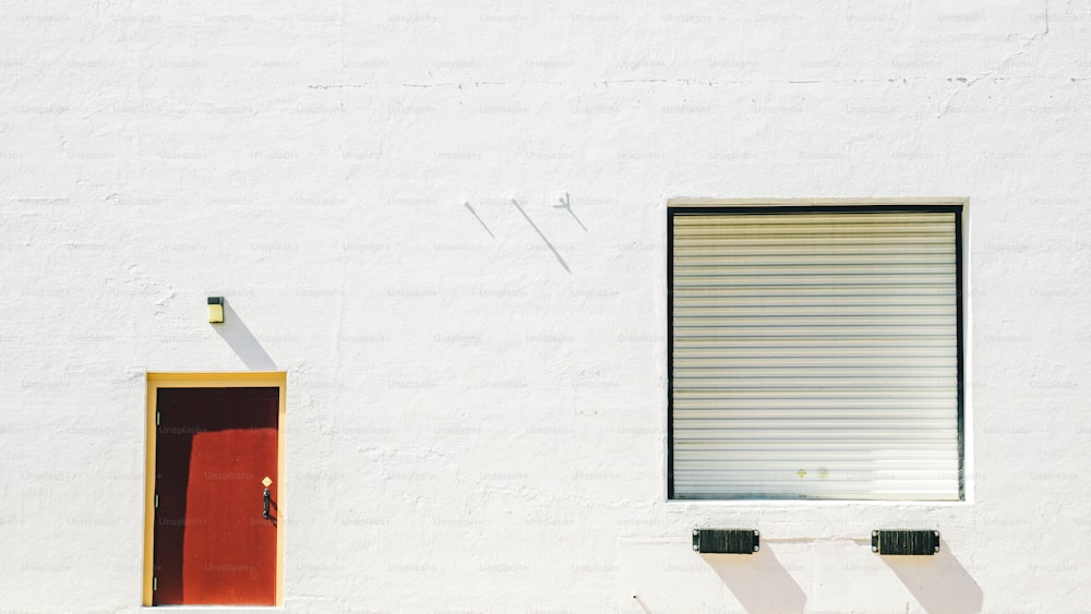 Un edificio blanco con una puerta y ventana rojas