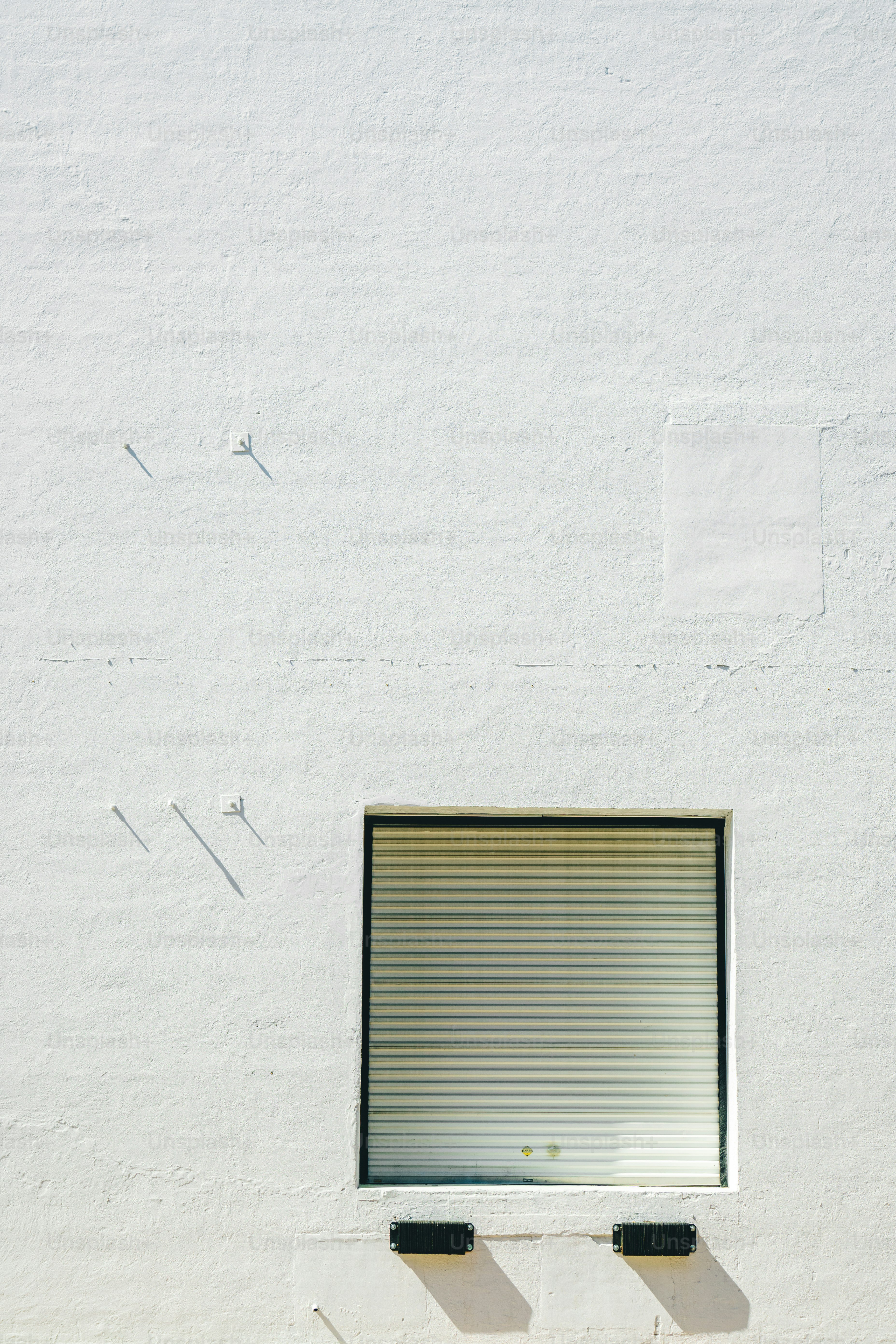 un edificio blanco con una ventana cerrada y un banco