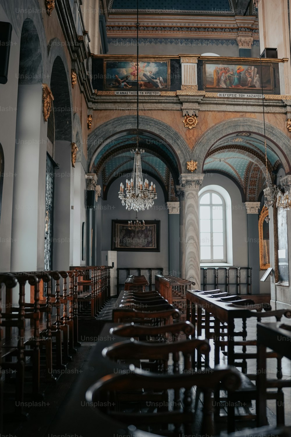 a church with pews and chandeliers hanging from the ceiling