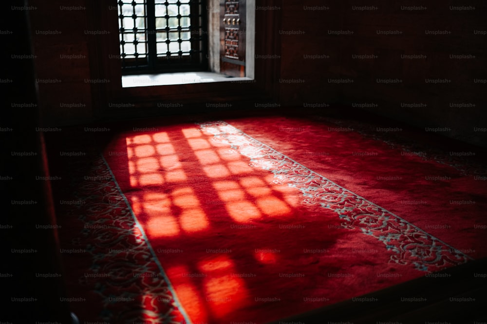 una habitación con una alfombra roja y una ventana