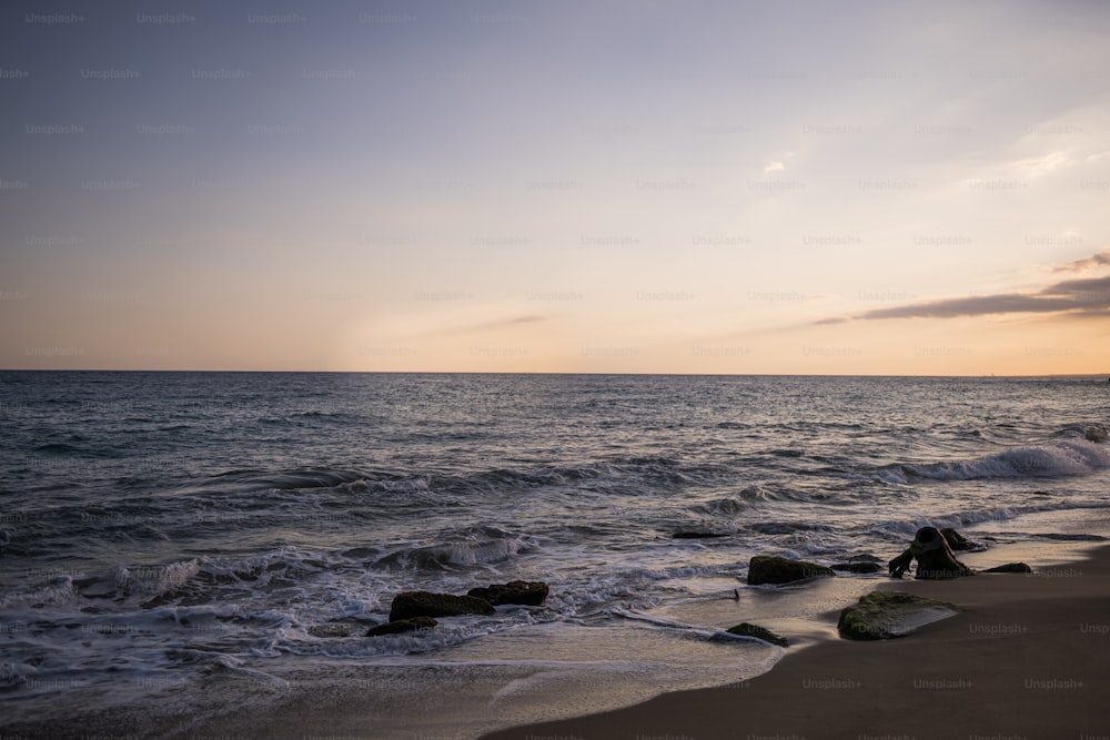 une personne assise sur un rocher près de l’océan