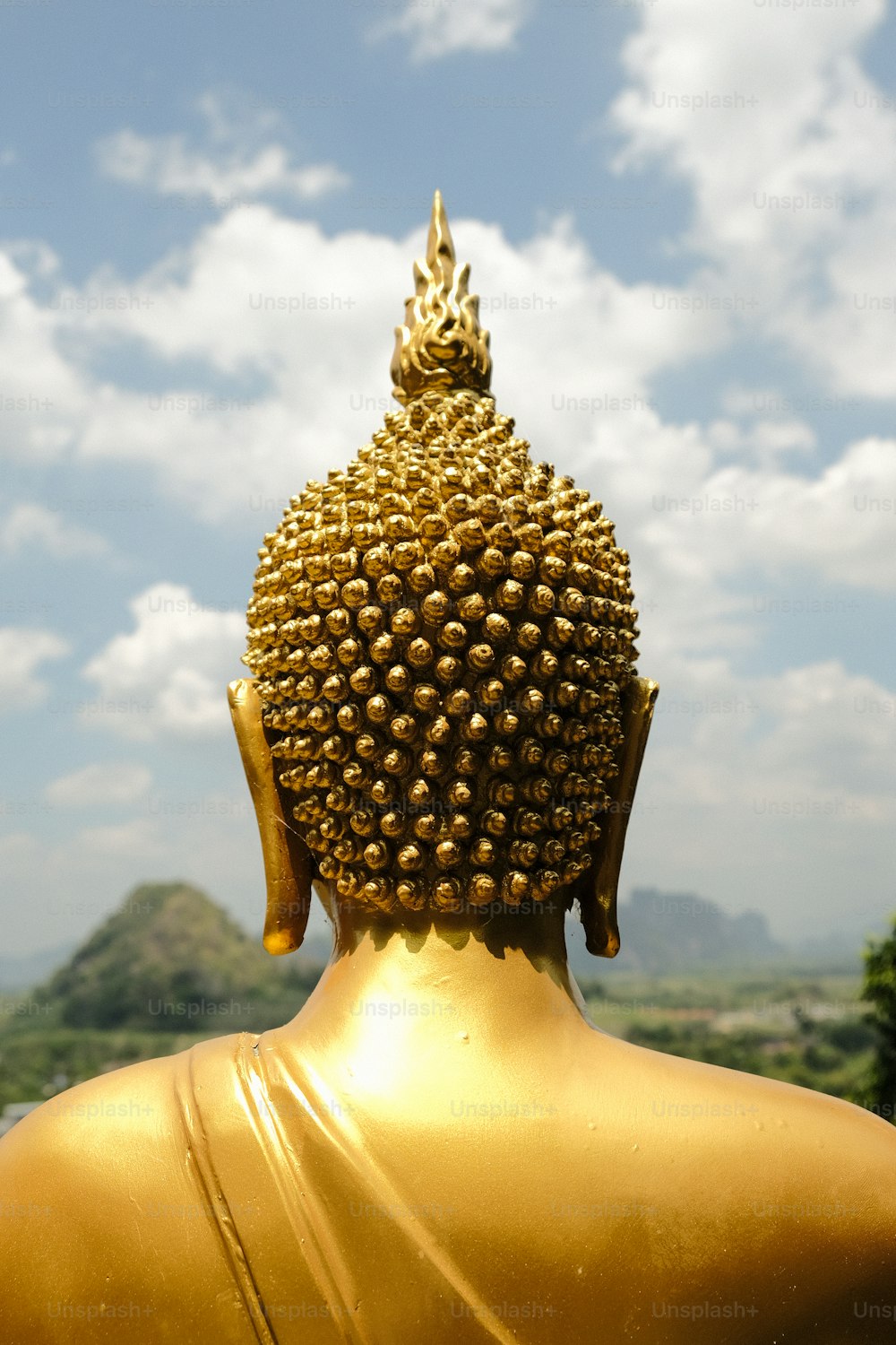 a golden buddha statue sitting in front of a blue sky