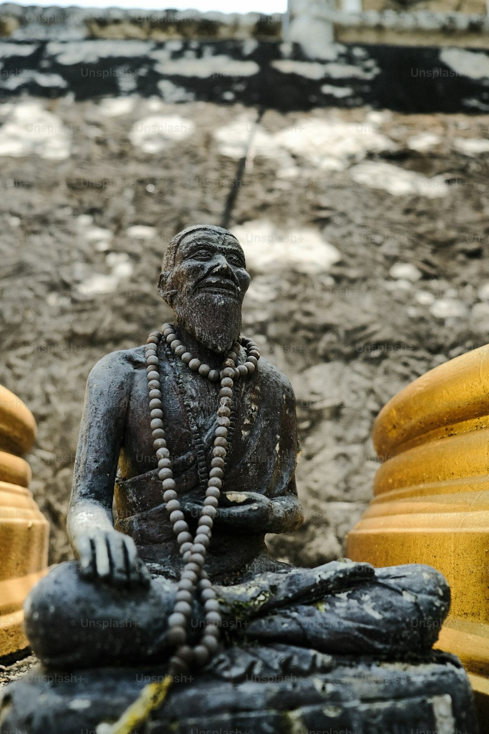 Una statua di un uomo seduto accanto a un idrante giallo