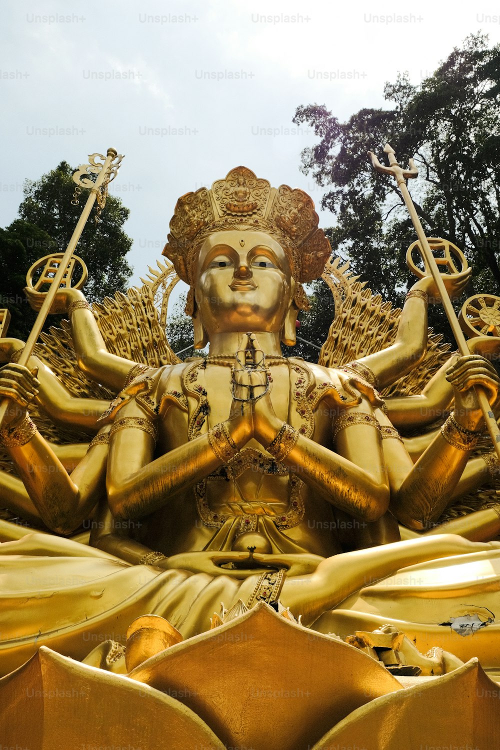 a golden statue of a person holding two swords