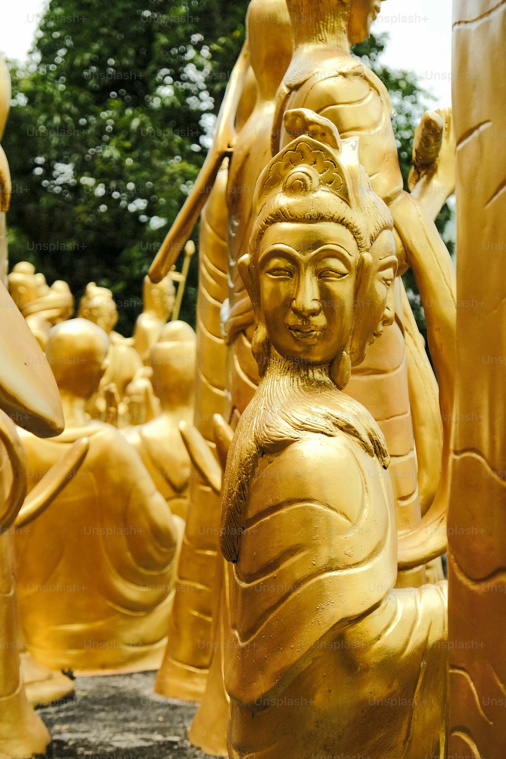 a group of golden statues of buddhas in a park