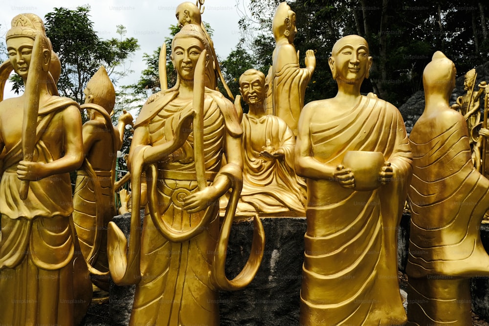 a group of golden statues of buddhas in a park