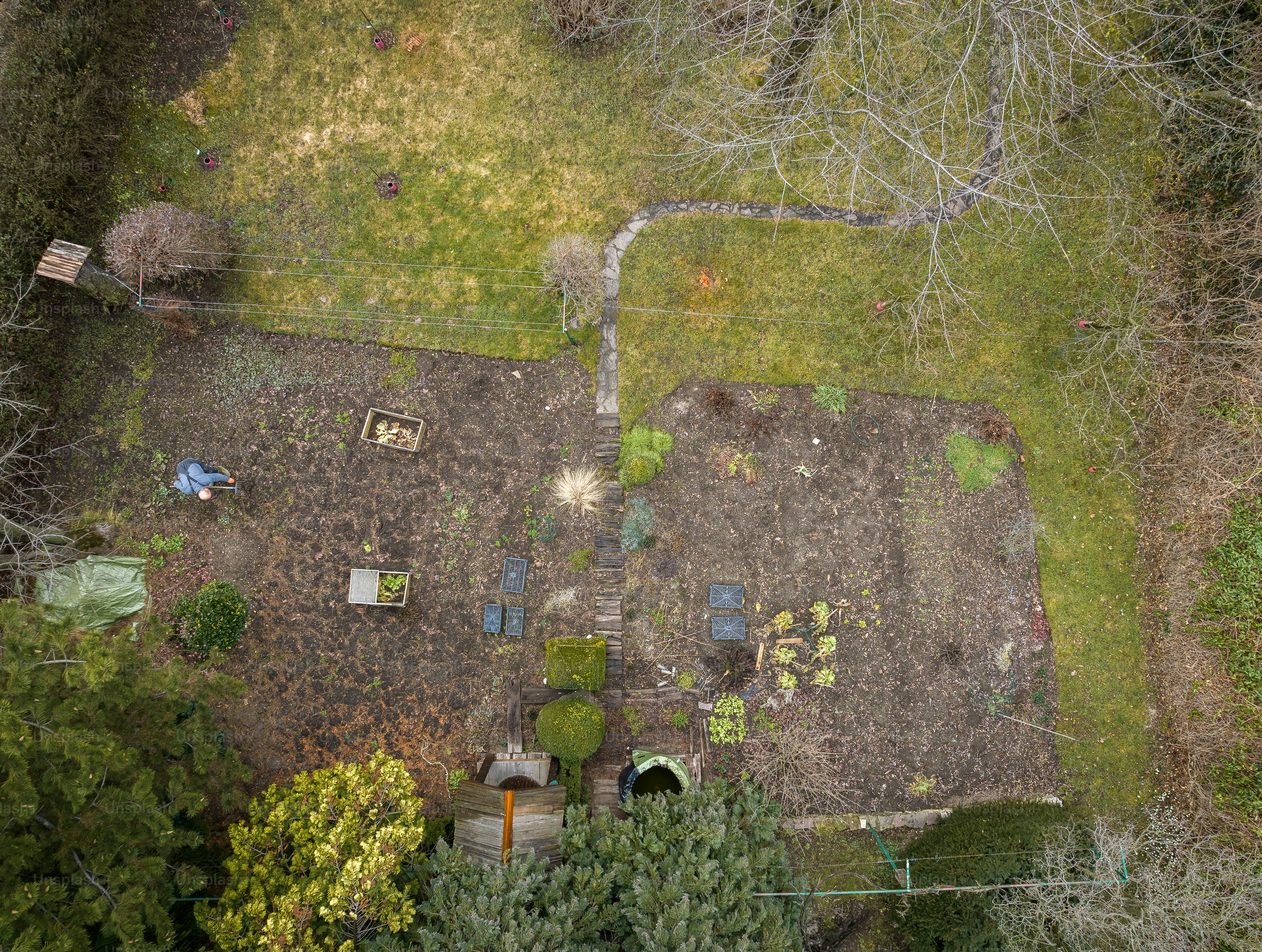 Aerial image of an elderly man taking care of his garden in the early spring.