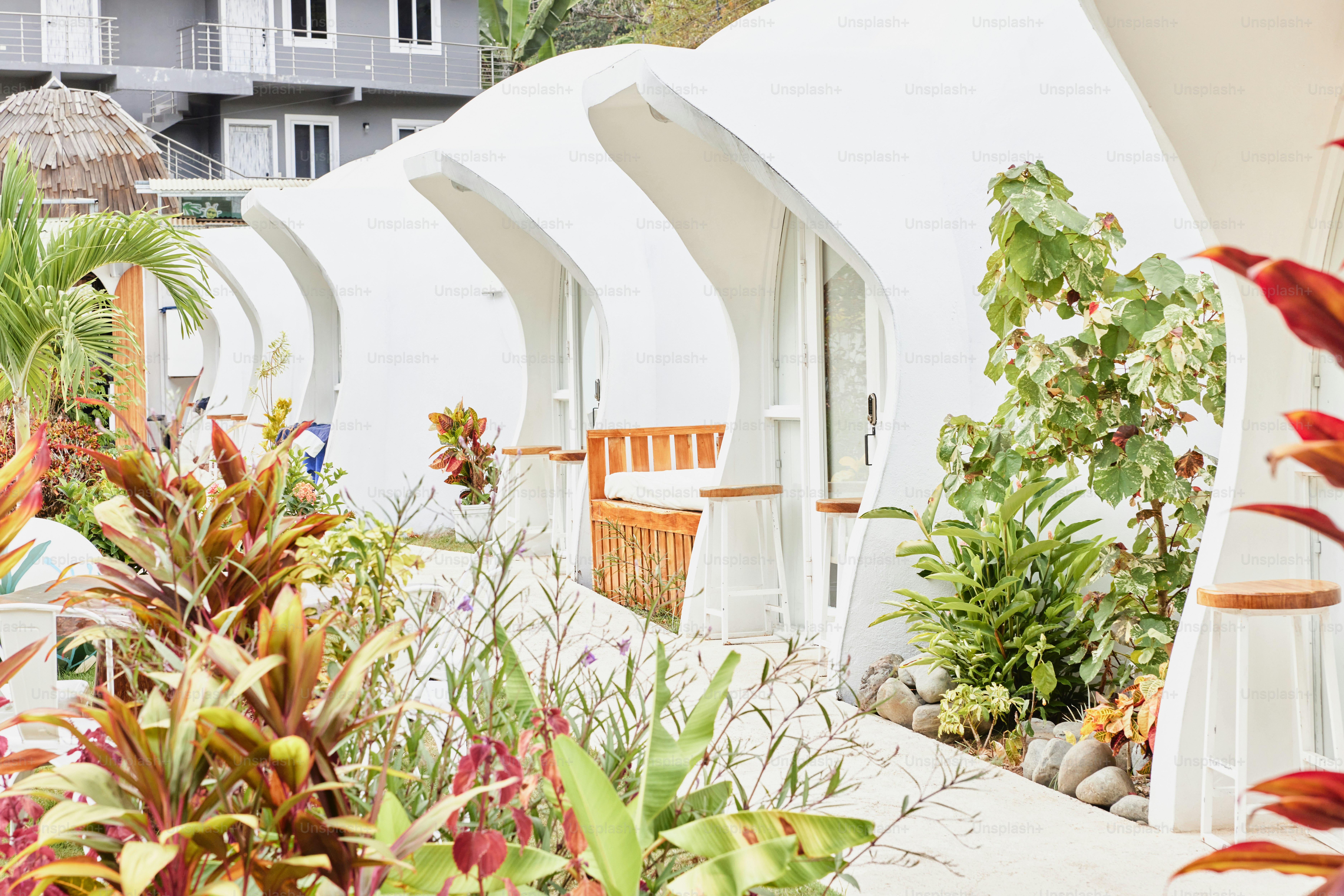 a row of white buildings with plants and a bench