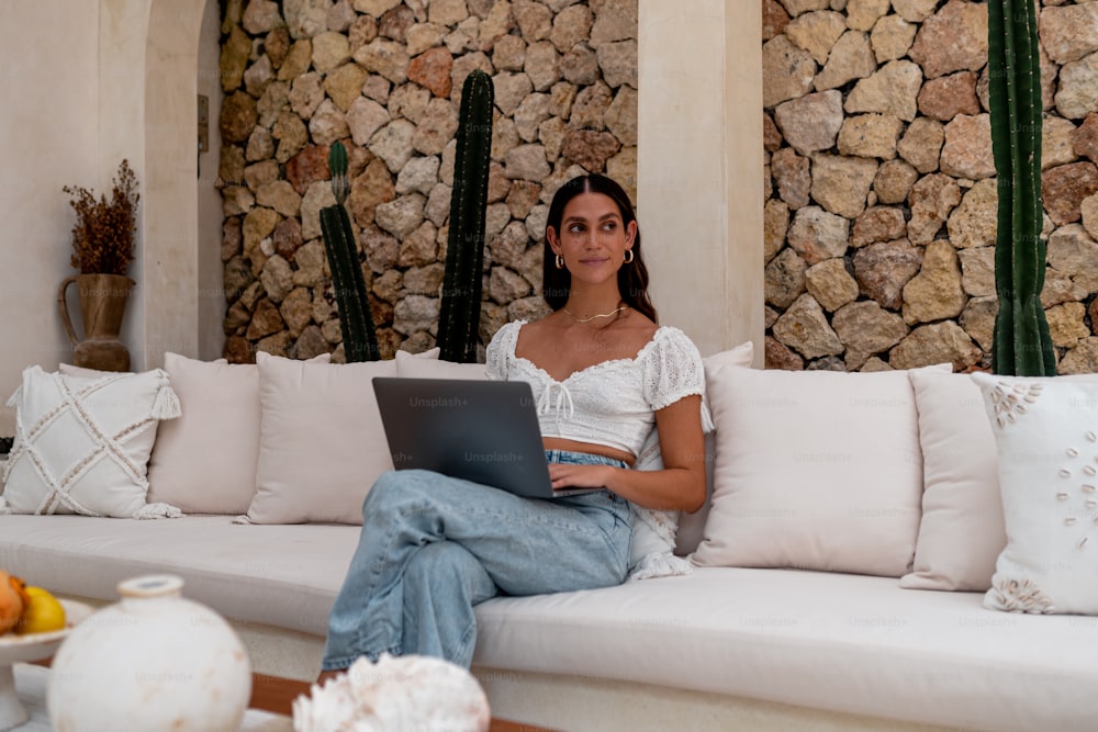 Una mujer sentada en un sofá con una computadora portátil