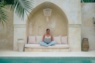 a woman sitting on a couch in front of a pool