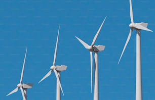 uma fileira de turbinas eólicas contra um céu azul