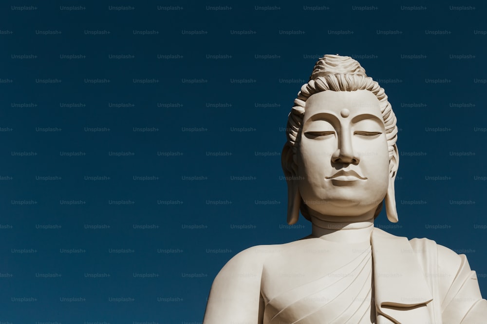Una statua bianca del Buddha con un cielo blu sullo sfondo