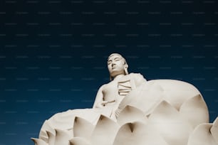 una statua di una persona seduta sulla cima di un fiore