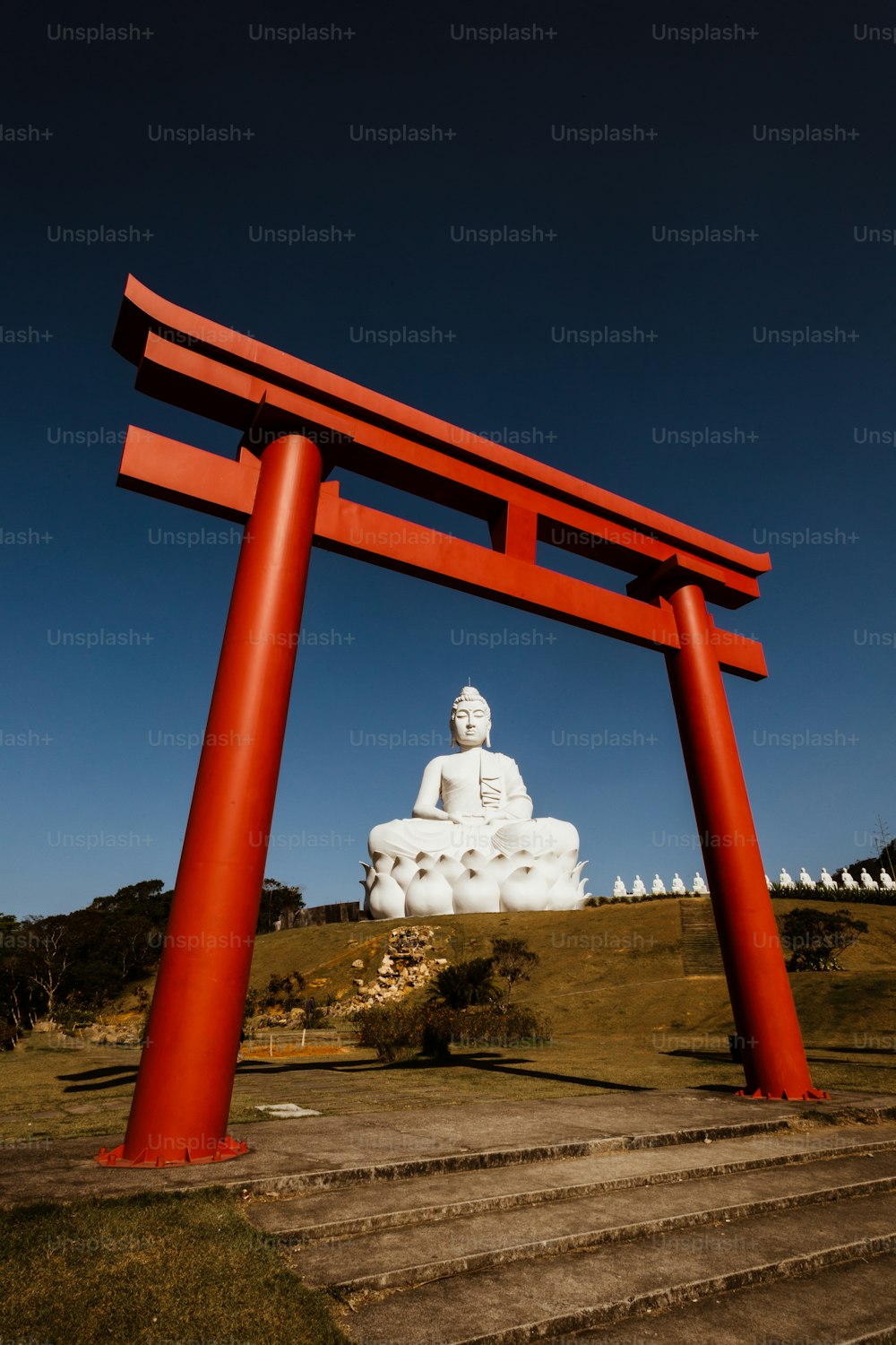 uma estátua de um buda na frente de uma grande estrutura vermelha