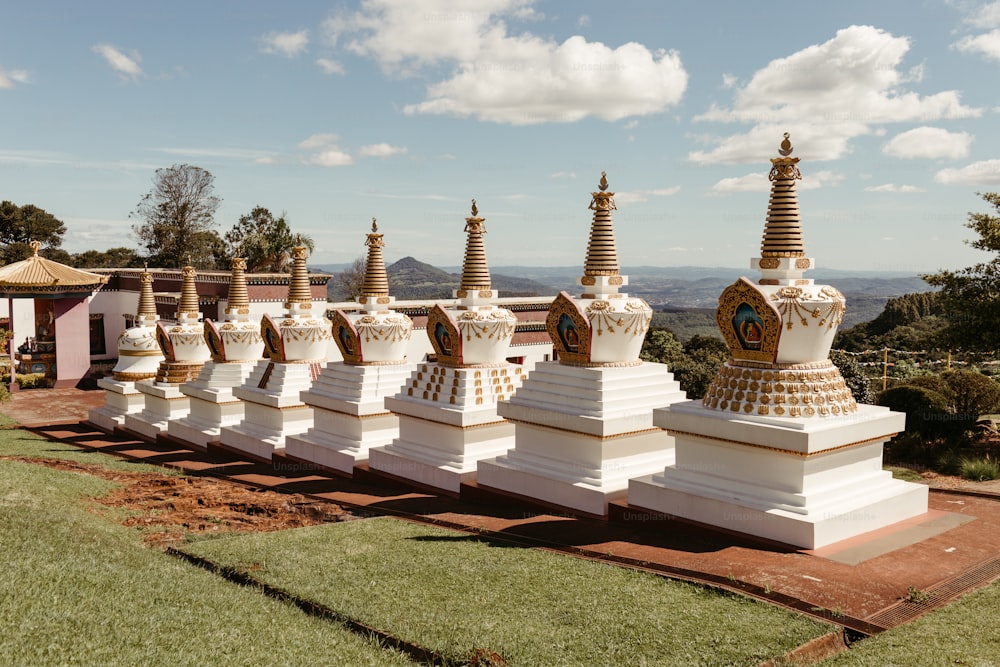 a row of white statues sitting on top of a lush green field