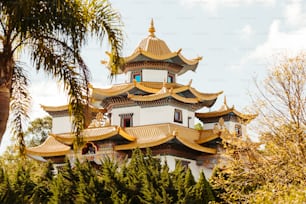 a tall white and gold building surrounded by trees