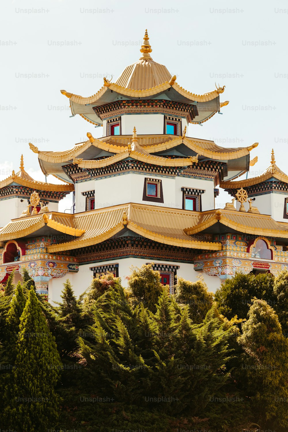 a tall white and gold building surrounded by trees