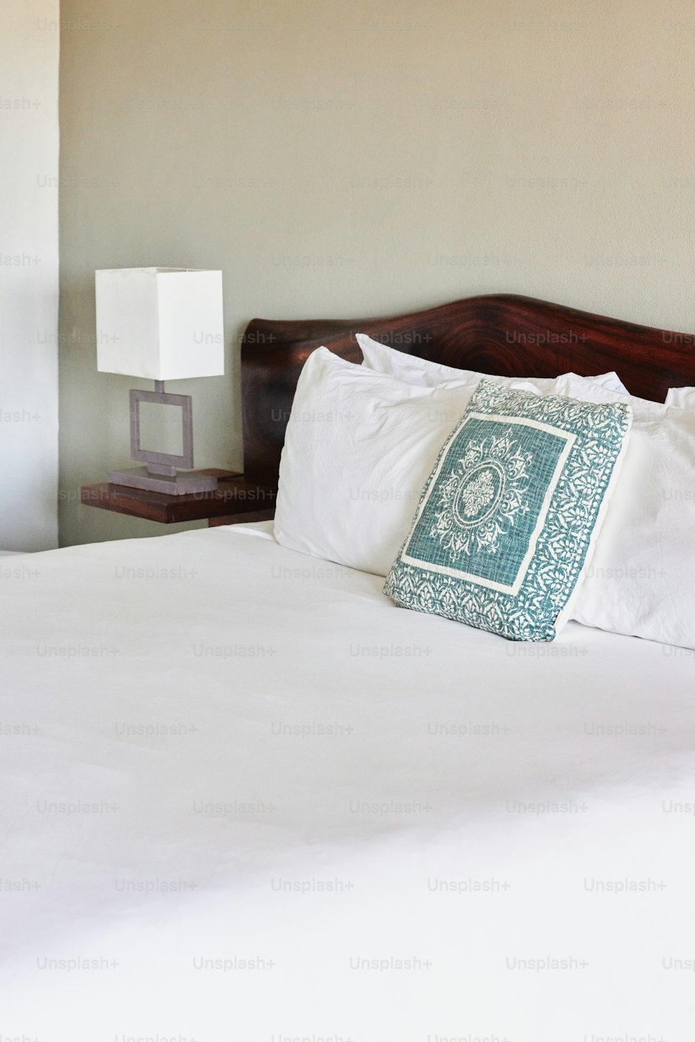 a bed with white sheets and a blue and white pillow