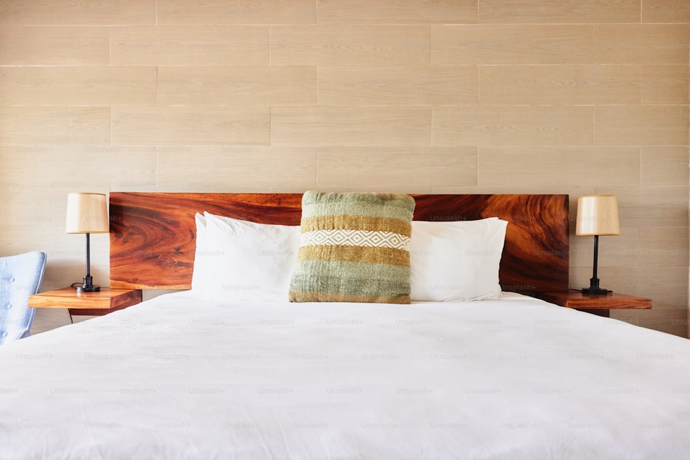 a bed with white sheets and pillows and a wooden headboard