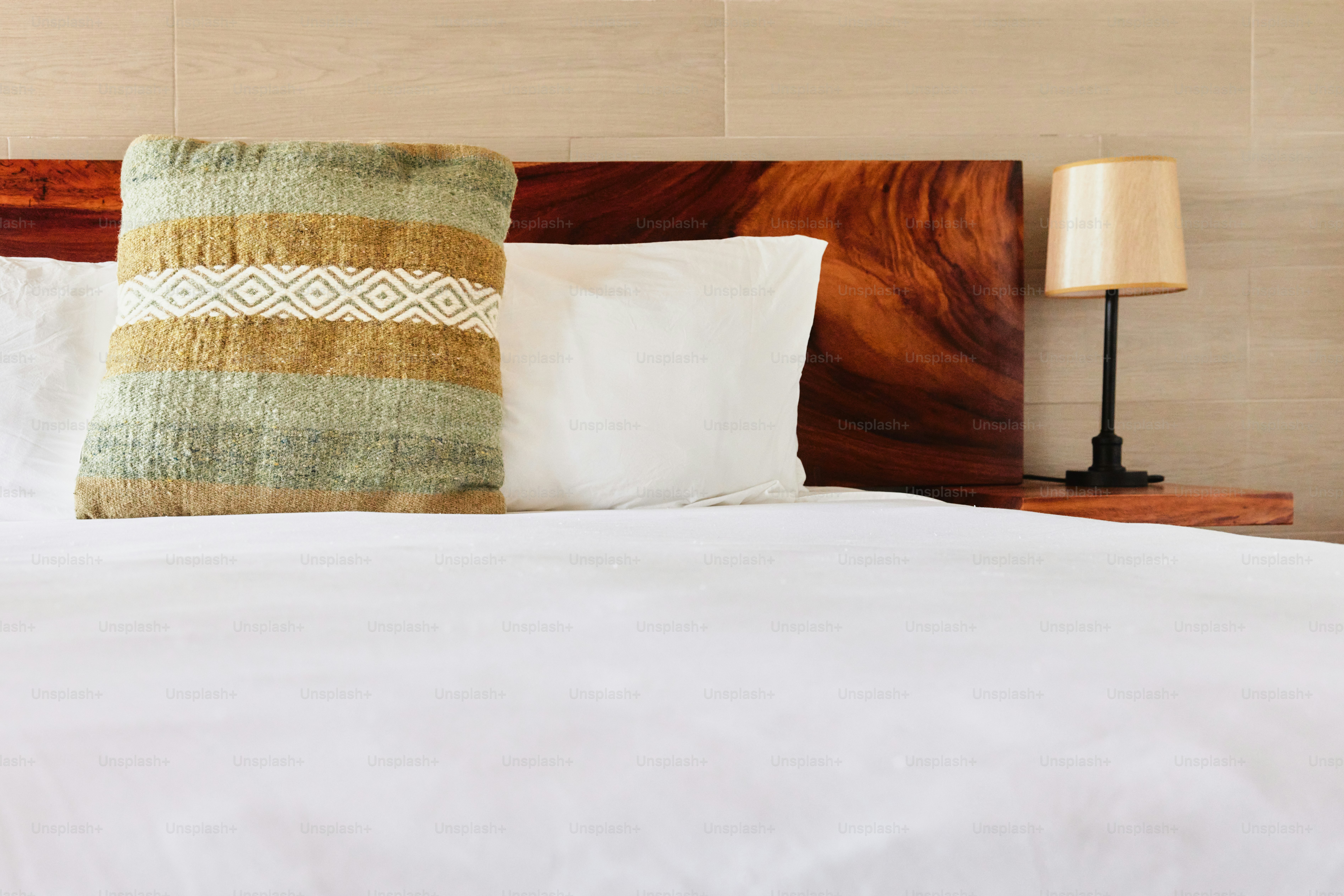 a bed with a white comforter and a wooden headboard