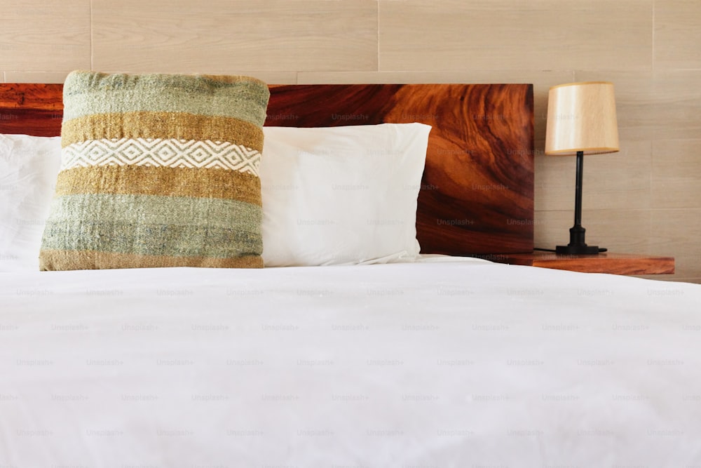 白い掛け布団と木製のヘッドボードを備えたベッド