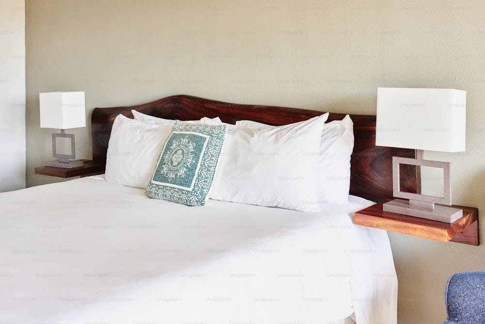 una cama con sábanas blancas y un cabecero de madera