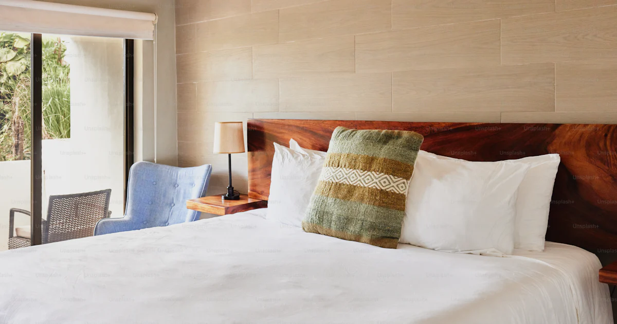 Un dormitorio con una cama y una silla foto – Imagen de Casa en Unsplash