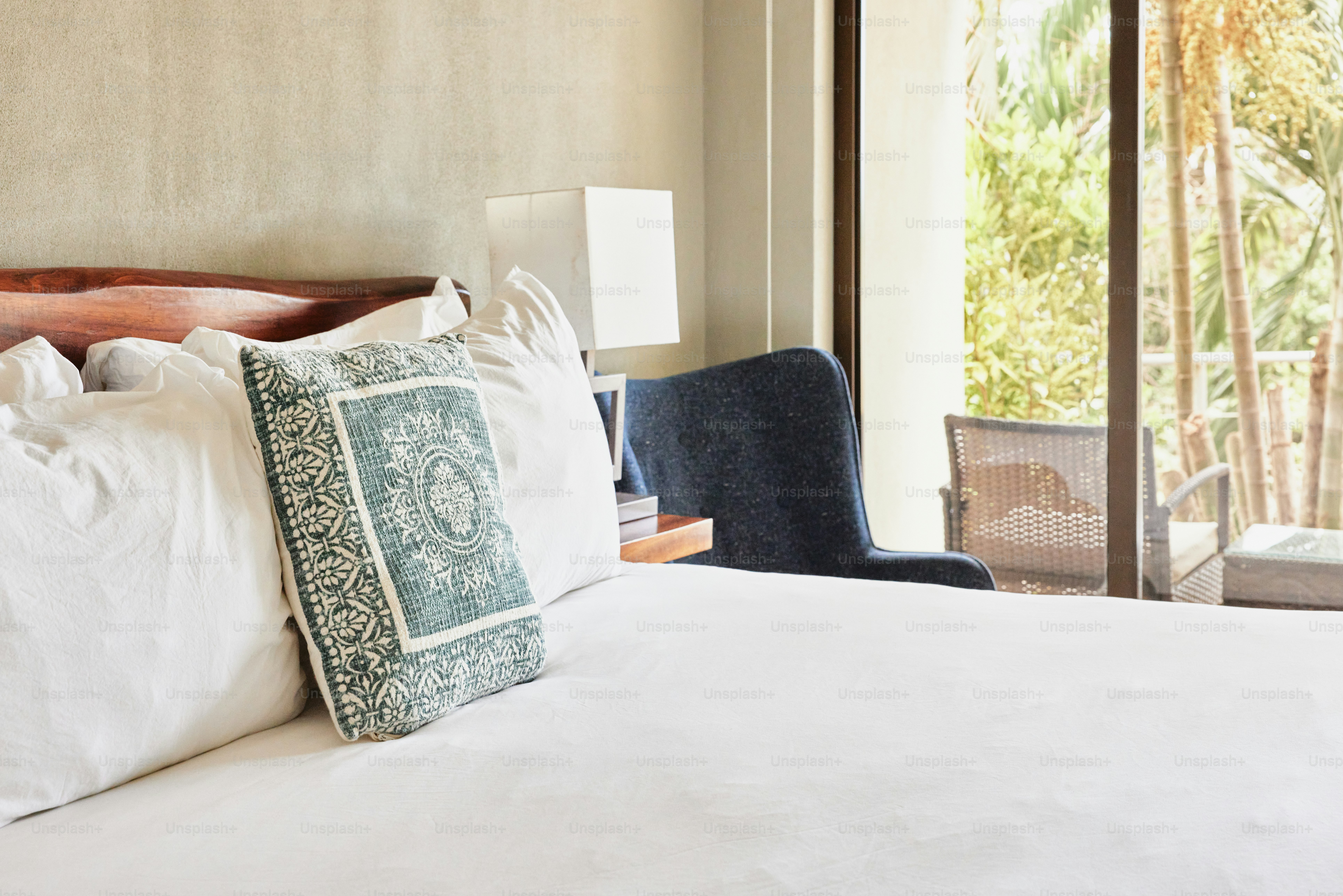 a bed with white sheets and pillows in a bedroom