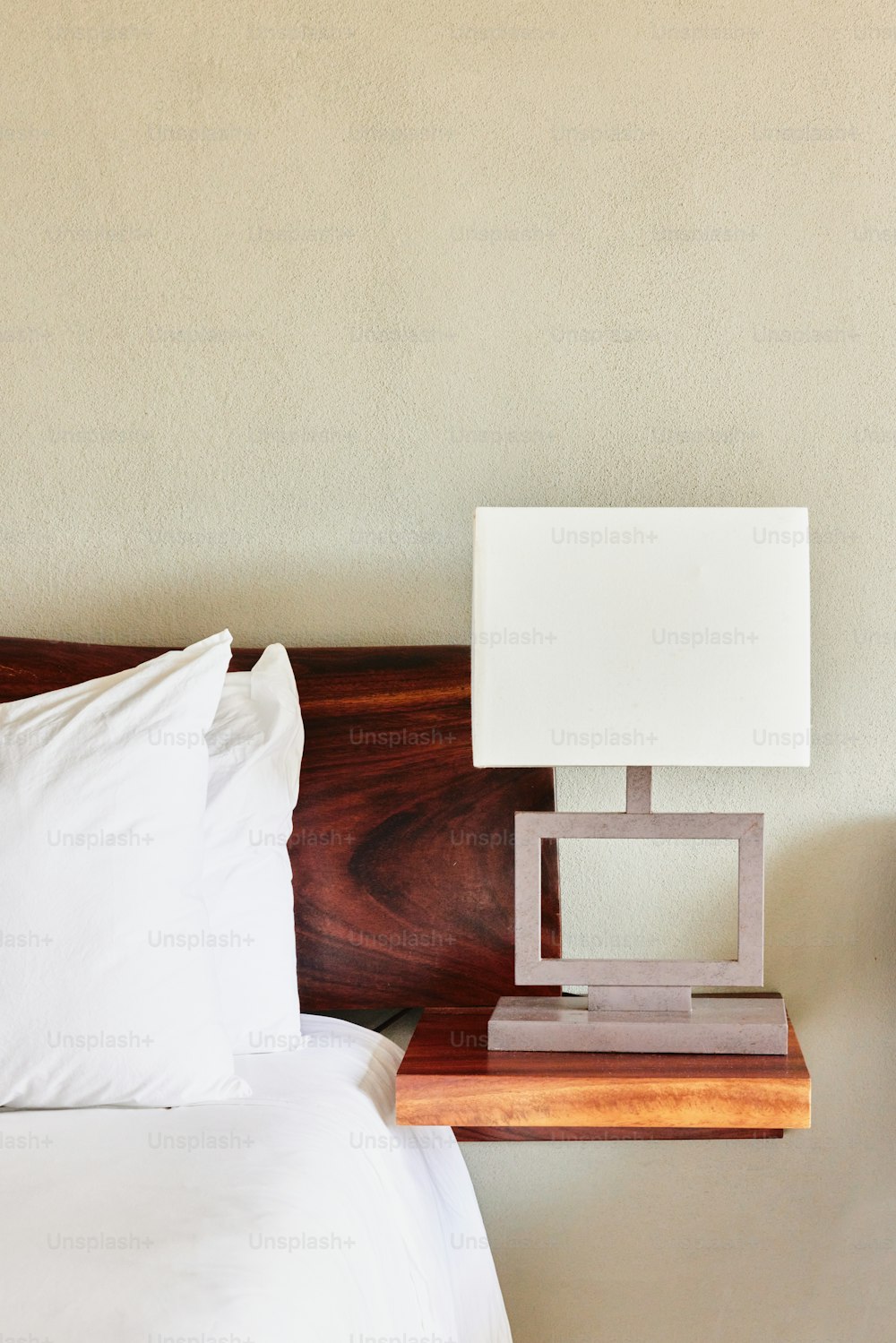 a bed with a white pillow and a wooden night stand