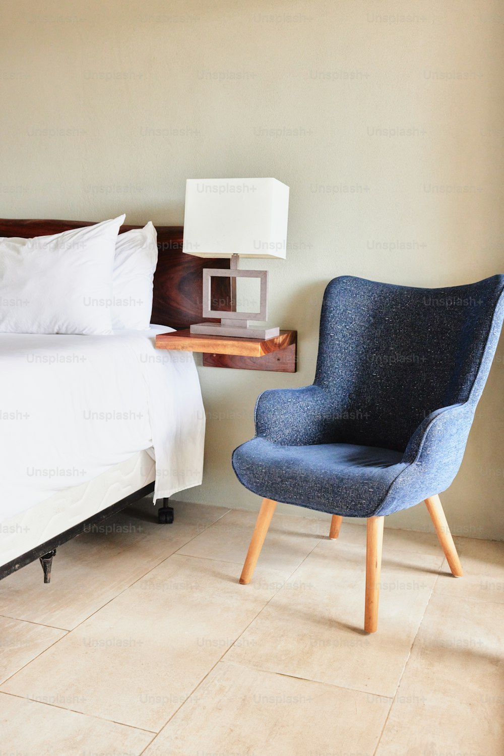 Una silla azul sentada junto a una cama en un dormitorio