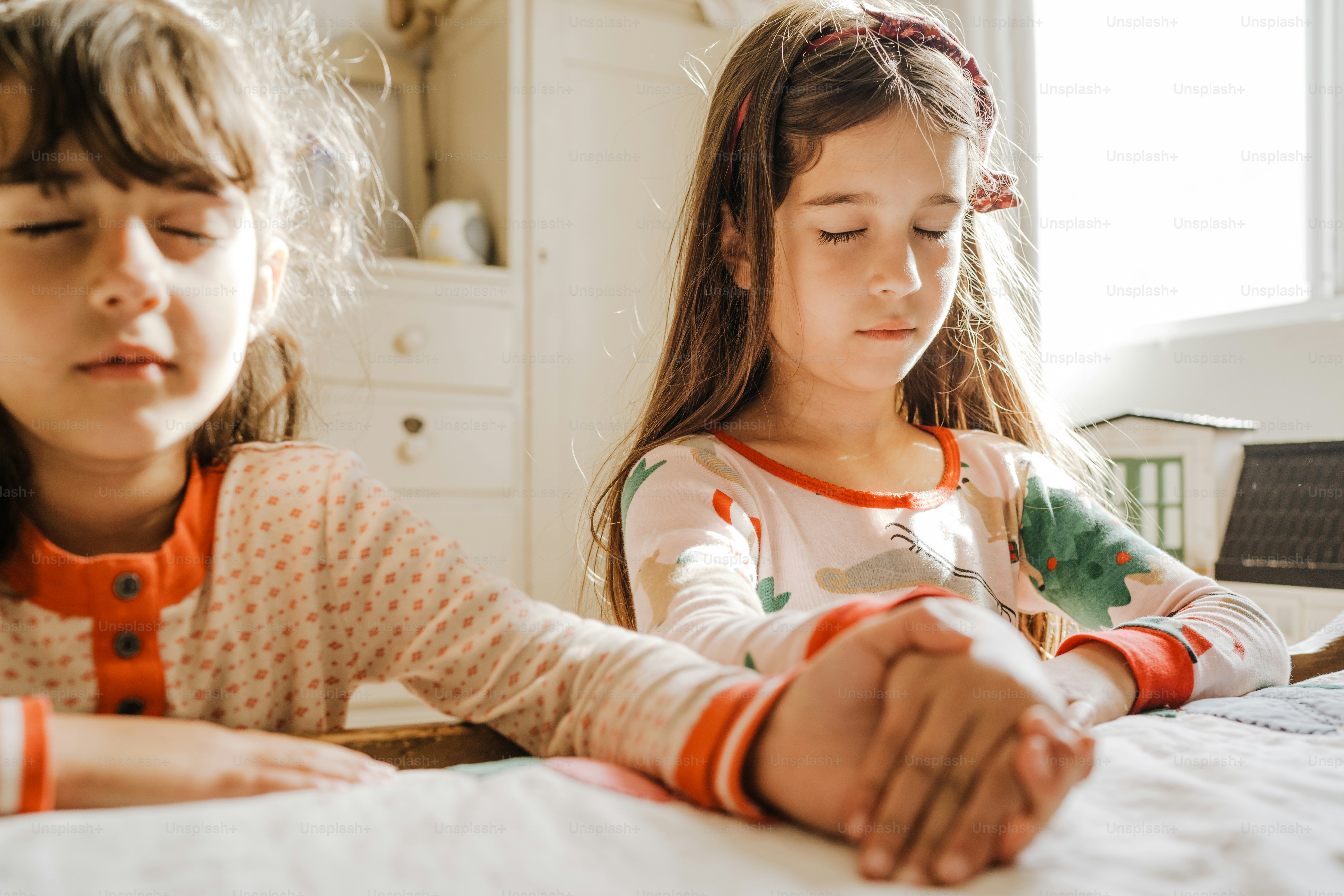 Due bambine sedute a un tavolo con le mani unite