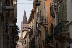 a narrow city street with a church steeple in the background