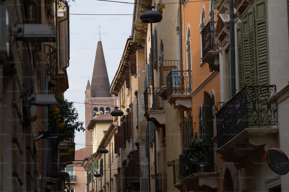 a narrow city street with a church steeple in the background