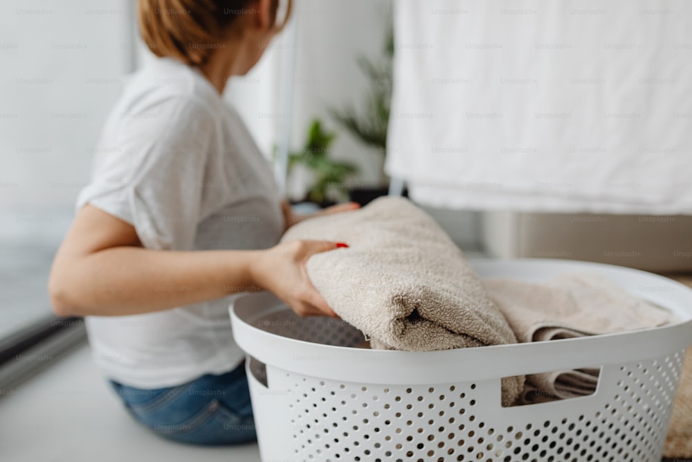 uma mulher sentada em um cesto de lavanderia com uma toalha