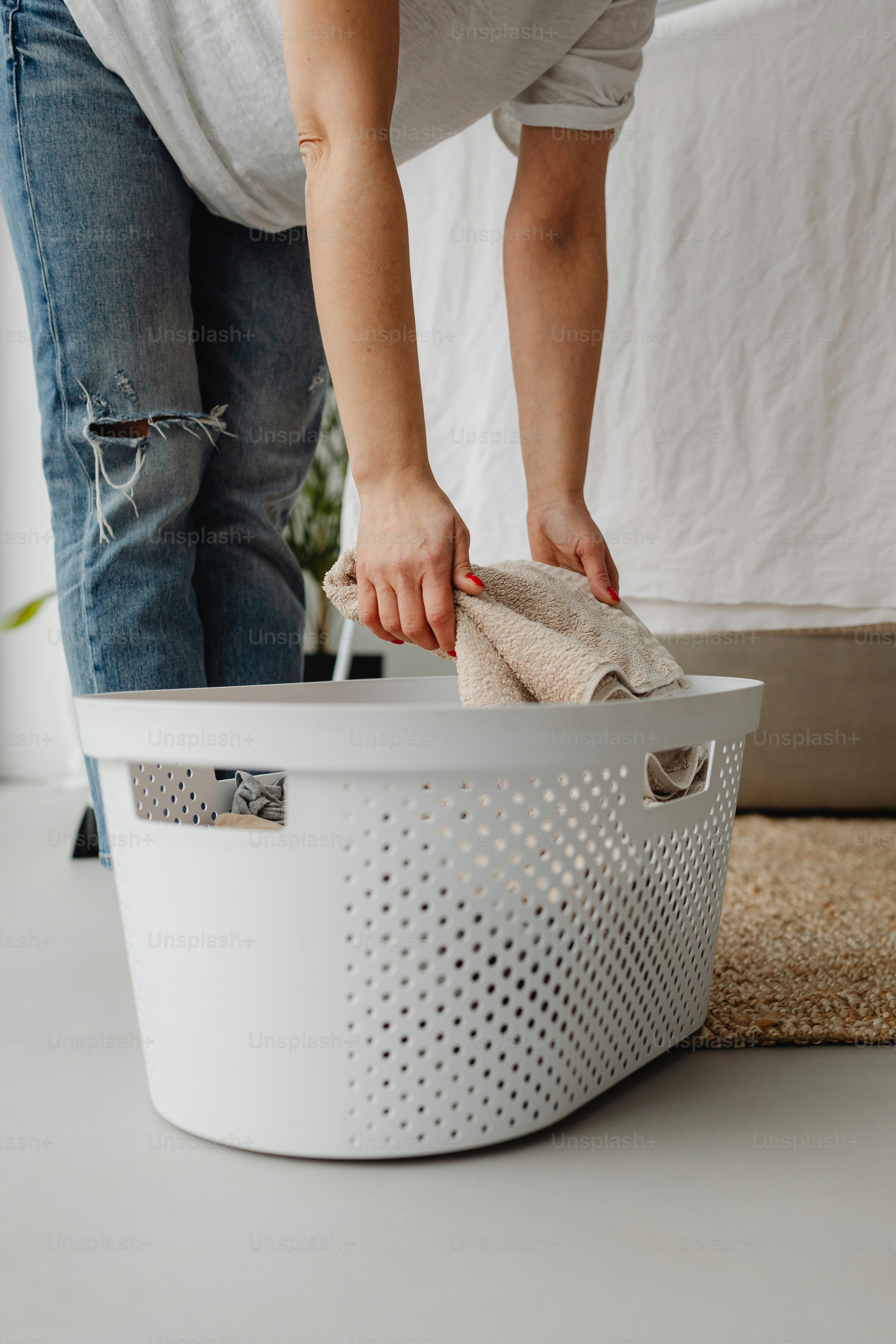 a woman cleaning a laundry basket with a rag