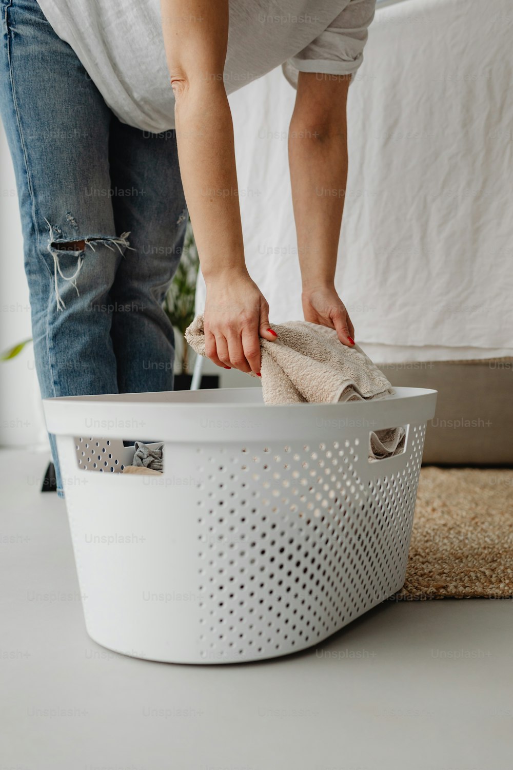 a woman cleaning a laundry basket with a rag