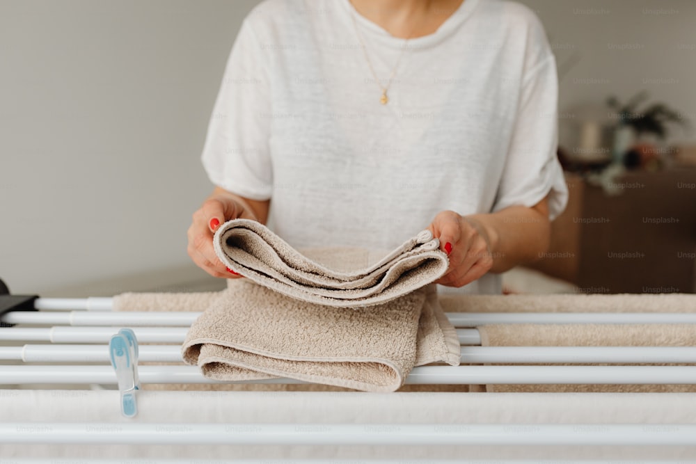 a woman holding a cloth over a bed rail